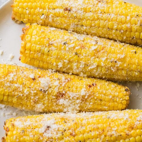 Garlic Parmesan Grilled Corn on a white plate on a grey background
