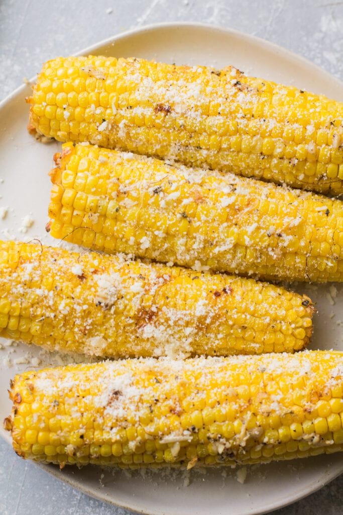 Garlic Parmesan Grilled Corn on a white plate on a grey background