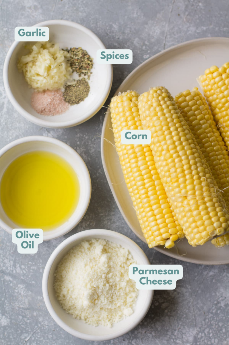 Ingredients for garlic parmesan corn in small white bowls on a grey background.