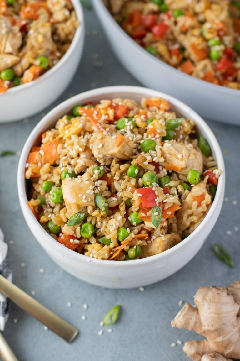 An overhead bowl of Healthy Fried Rice on a grey background with fried rice in the background