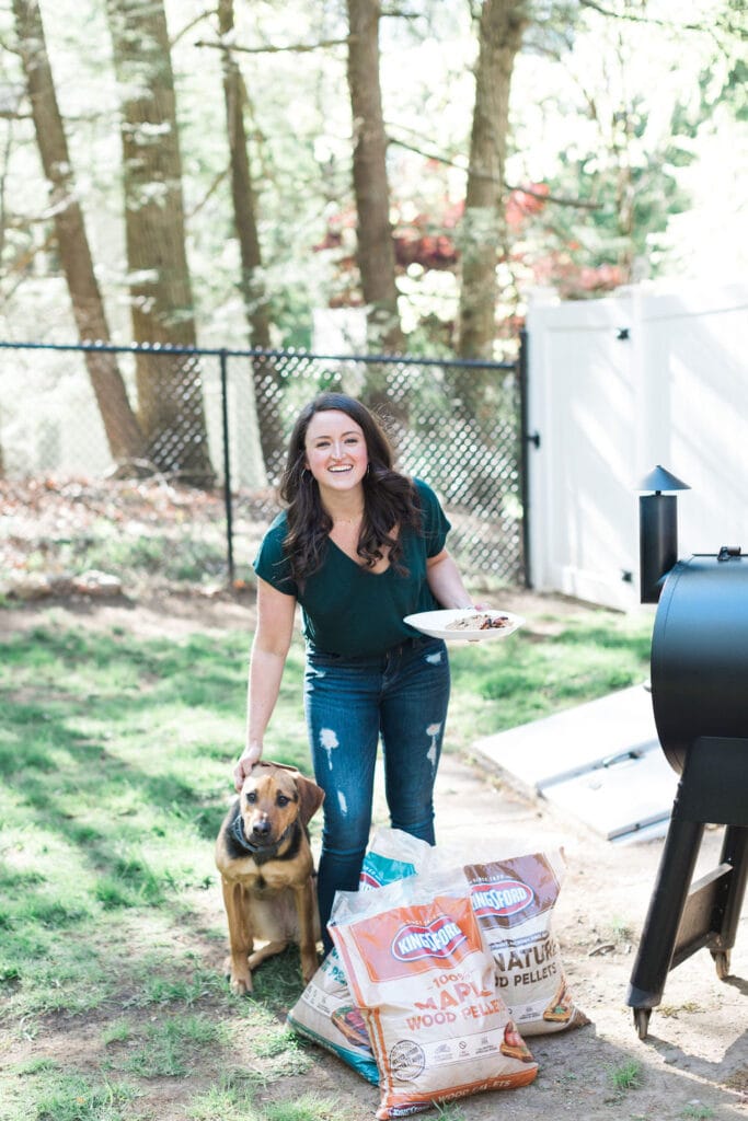 A girl holding a plate grilling in a backyard