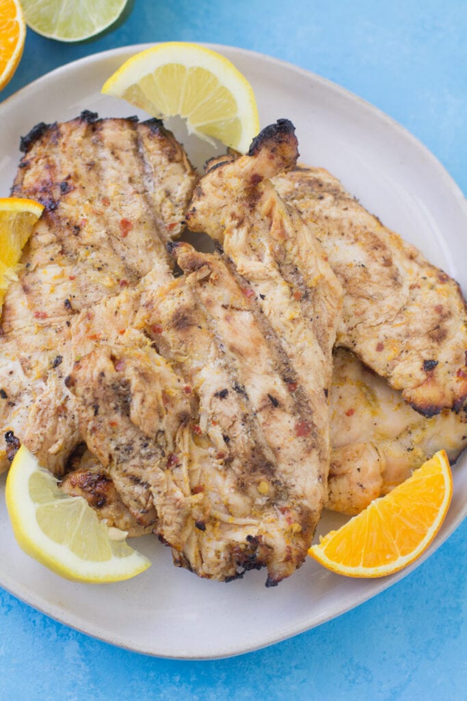 An overhead image of spicy citrus grilled chicken on a plate with citrus slices along the sides