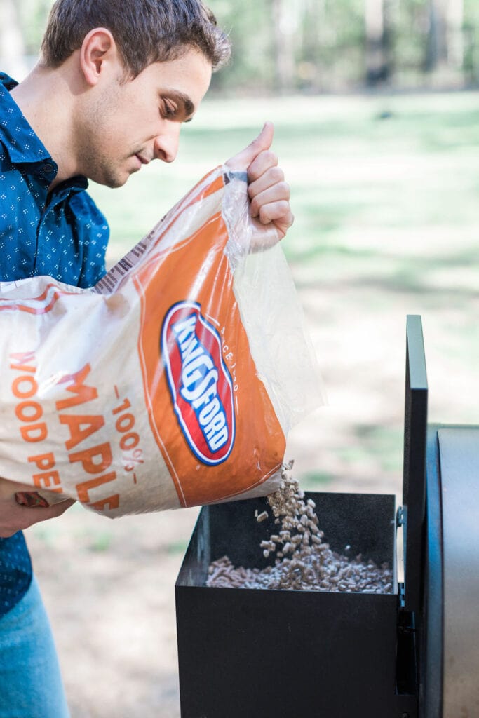 A man pour Kingsford pellets into a pellet grill