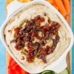 White Bean Hummus in a small white bowl on a cutting board with veggies and chips