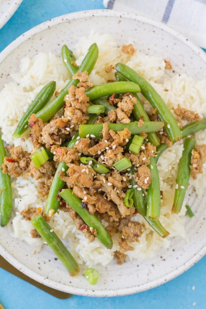 A close up of healthy ground turkey stir fry on top of rice with green beans