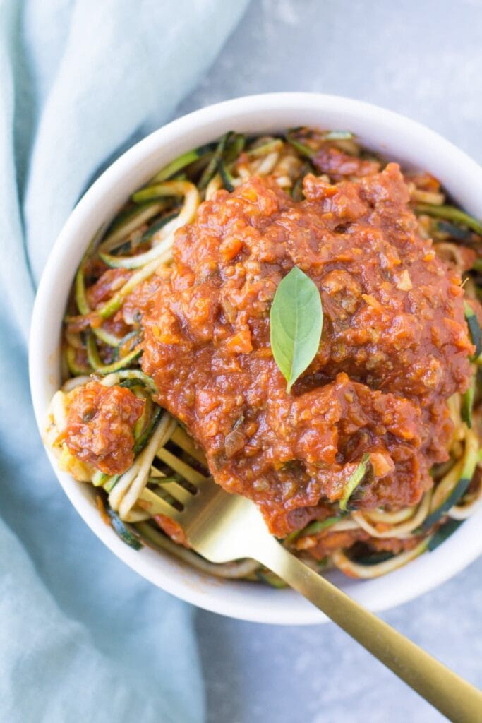 Healthy Turkey Bolognese in a bowl with zoodles and a gold fork