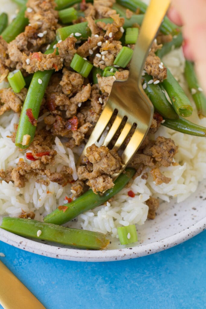 A gold fork taking a bit out of low carb turkey stir fry.