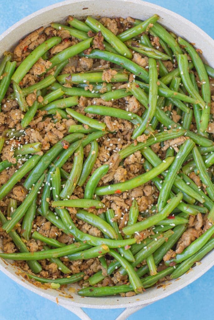A close up of ground turkey stir fry with green beans in a large grey pan.