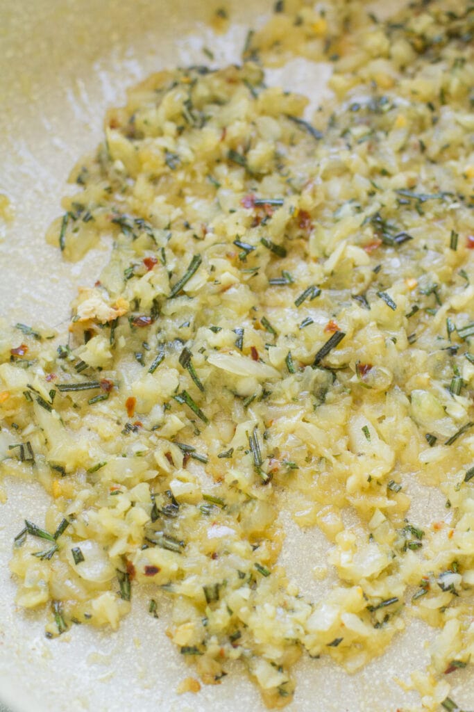 onions, garlic, herbs and spices sauteing in a pan for rosemary chicken sauce