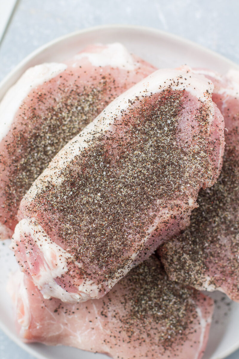 Uncooked pork chops rubbed with a coffee dry rub.