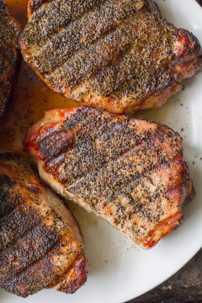A close up of grilled pork chops on a white plate