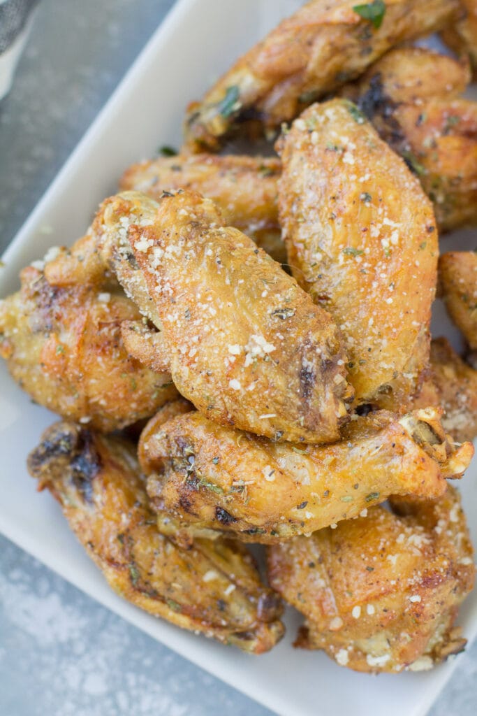 Garlic Parmesan Chicken Wings on a white plate on a grey background.