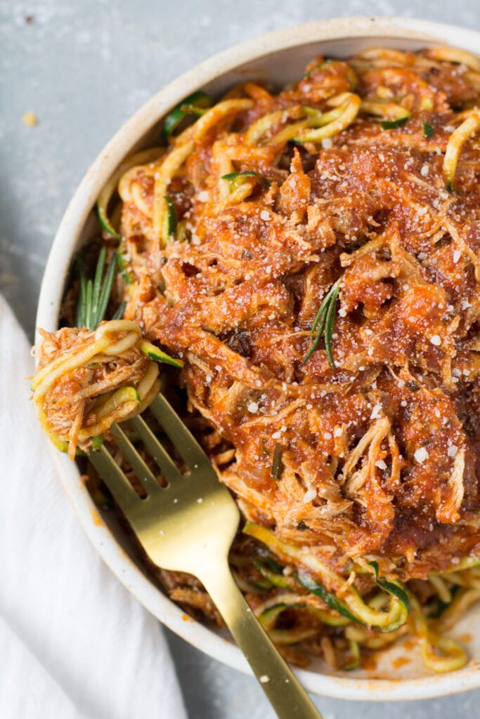 A fork with a swirl of zucchini noodles in a bowl of rosemary chicken sauce