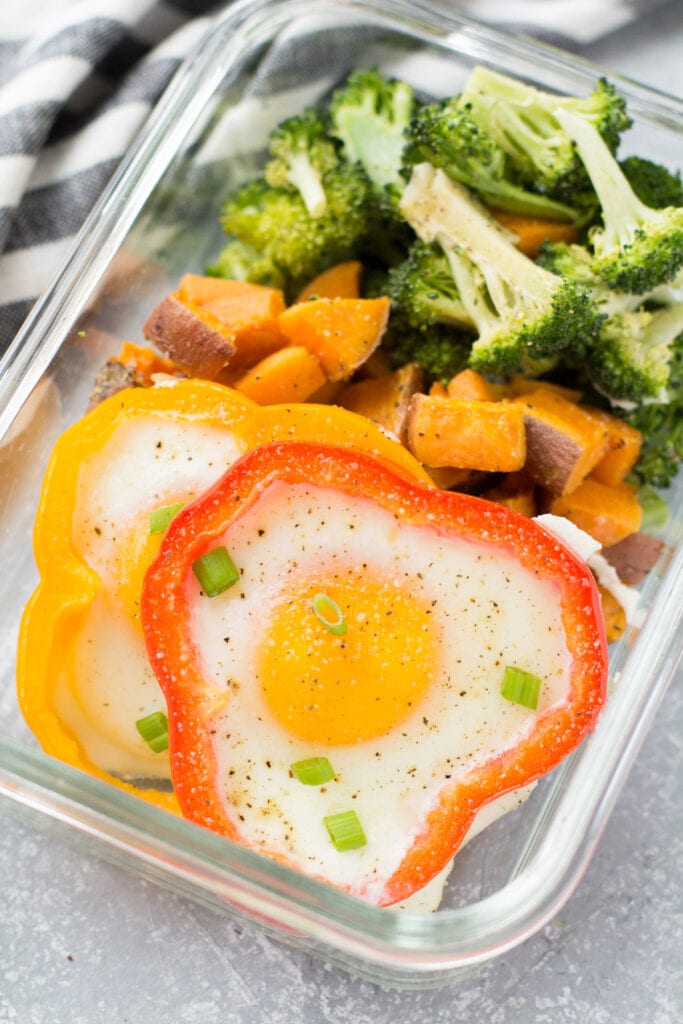 A close up image of sheet pan breakfast in a glass meal prep container