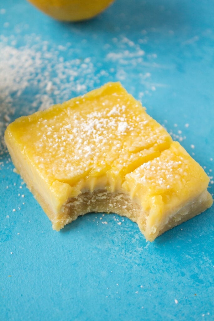 A close up of a lemon bar with a bite taken out of it.