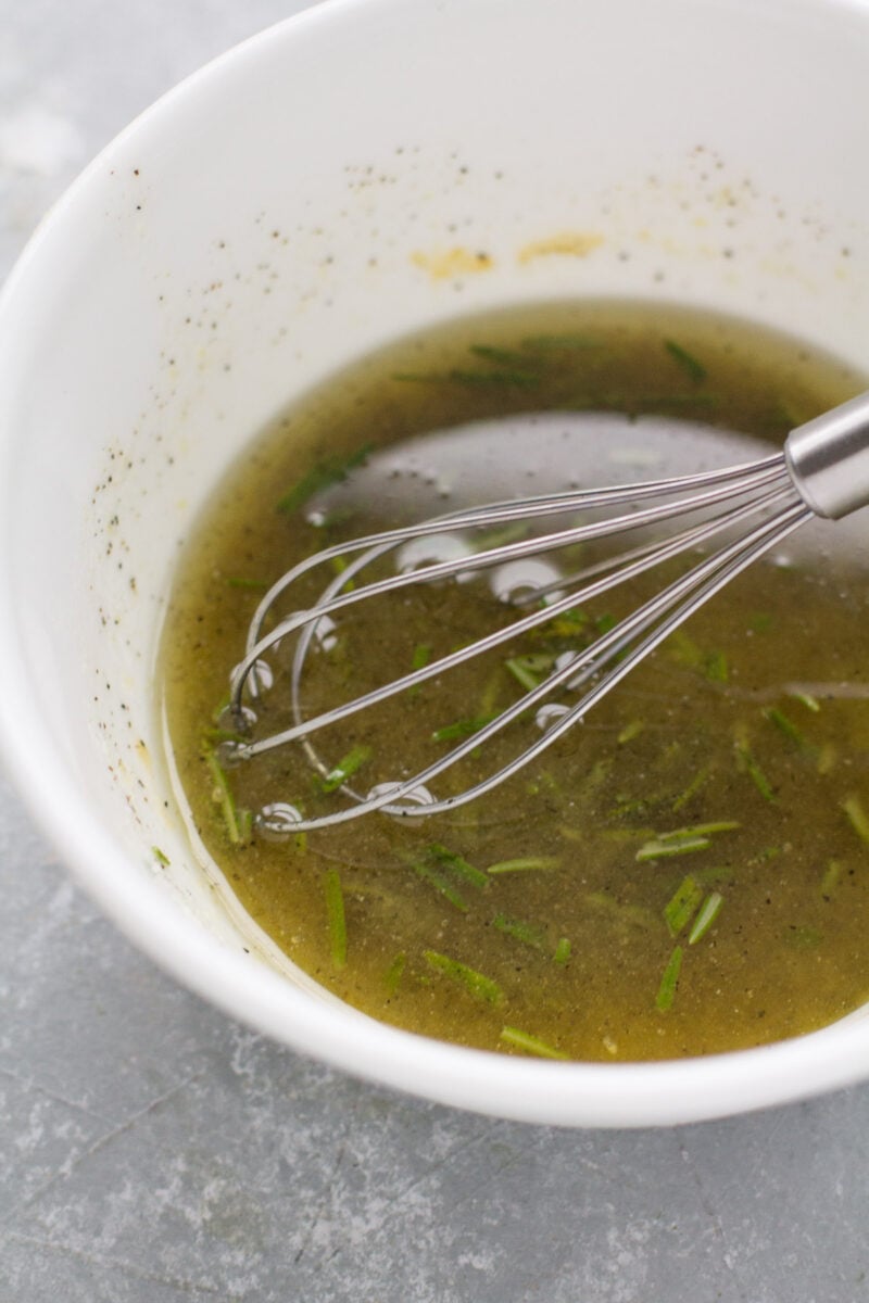 Lemon Rosemary Marinade in a bowl with a whisk in it.