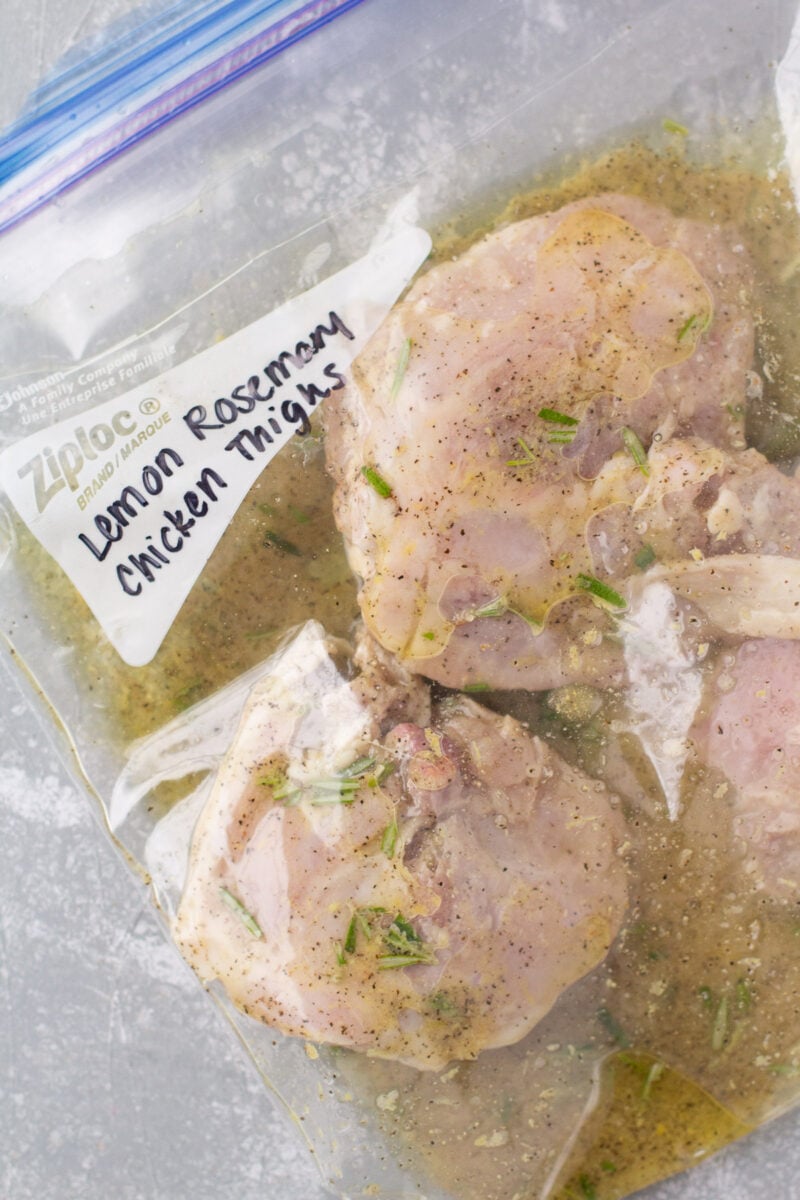 Chicken Thighs in a bag with lemon rosemary marinade with the words "Lemon Rosemary Chicken Thighs" written on the bag.