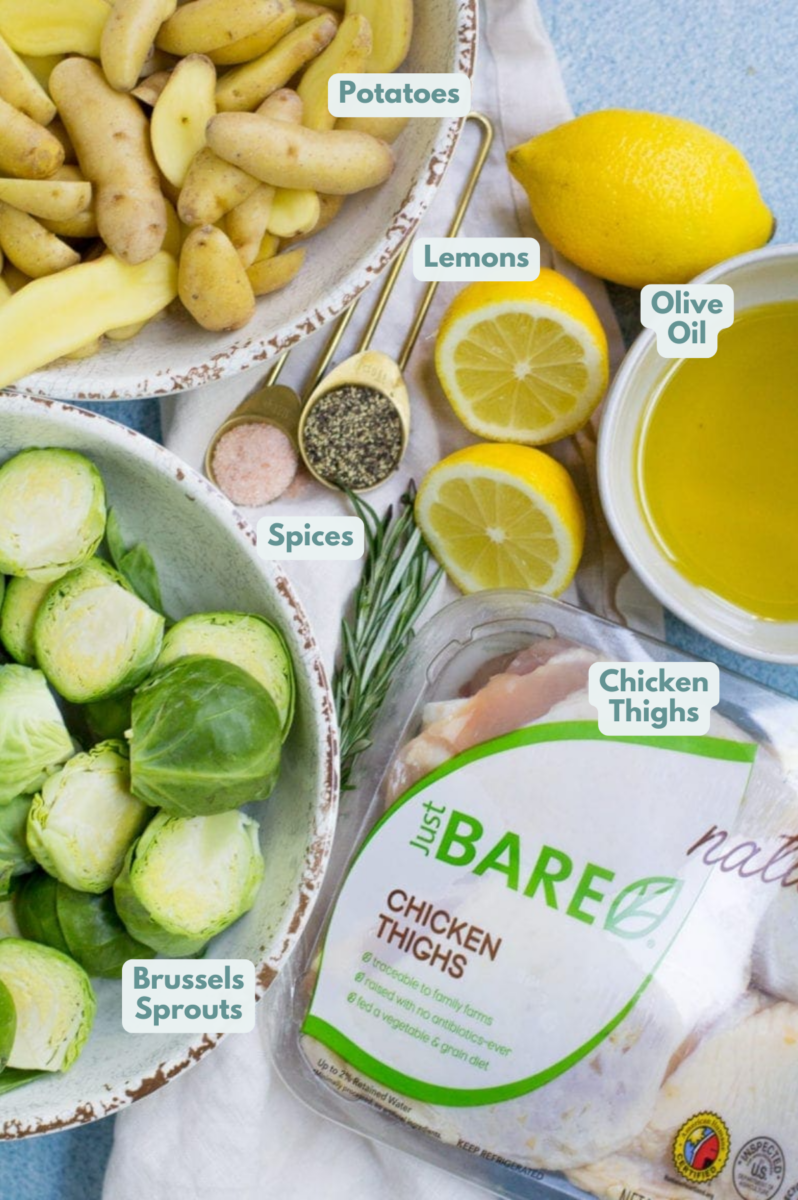 Ingredients for Lemon Rosemary Chicken Thighs. A bowl of potatoes, a bowl of brussels sprouts, lemons, spices and chicken thighs.
