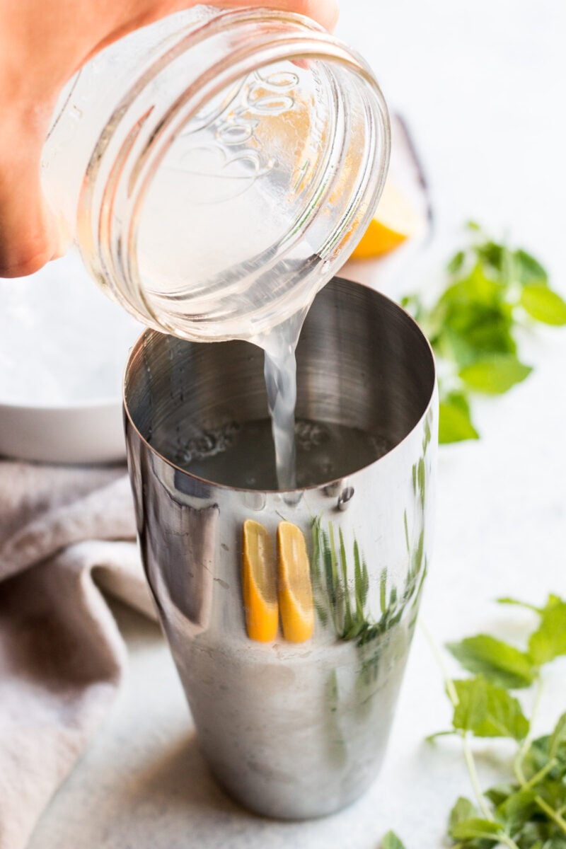 A hand pouring lemonade into a cocktail shaker. 