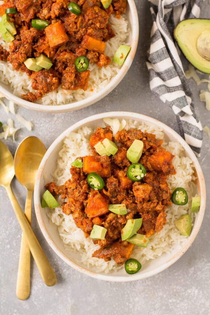 An overhead shot of two bowls of healthy chili with gold spoons off to the side
