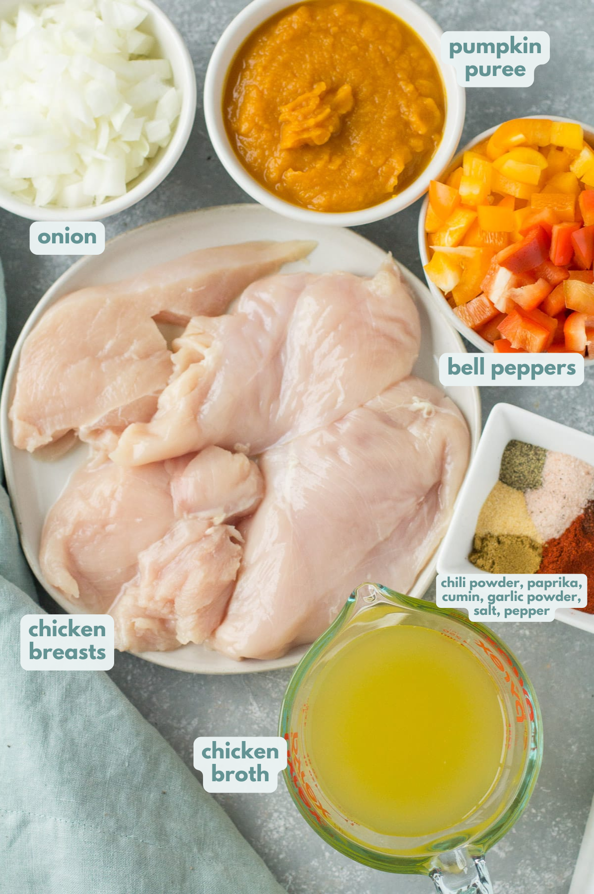 Ingredients for Pumpkin Chicken Chili on a grey background. The ingredients are in small white bowls.