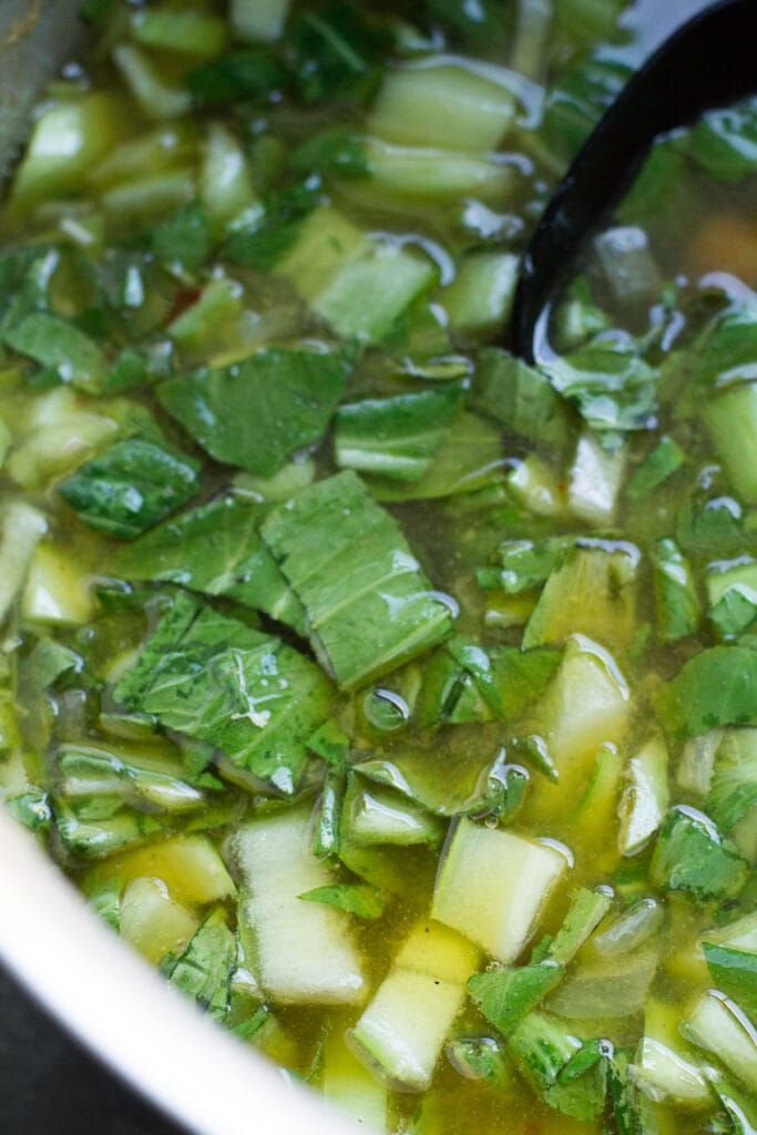 bok choy being stirred into asian chicken soup