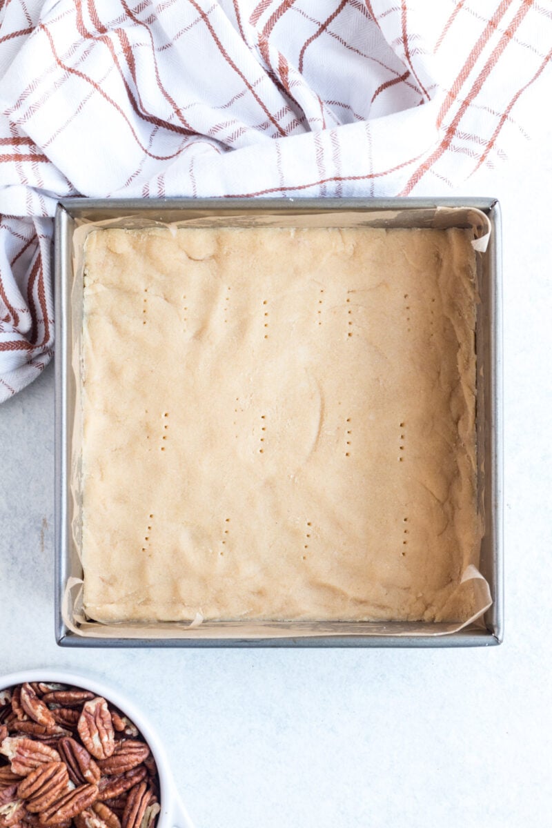 Pecan pie bar crust pressed into an 8x8 pan.
