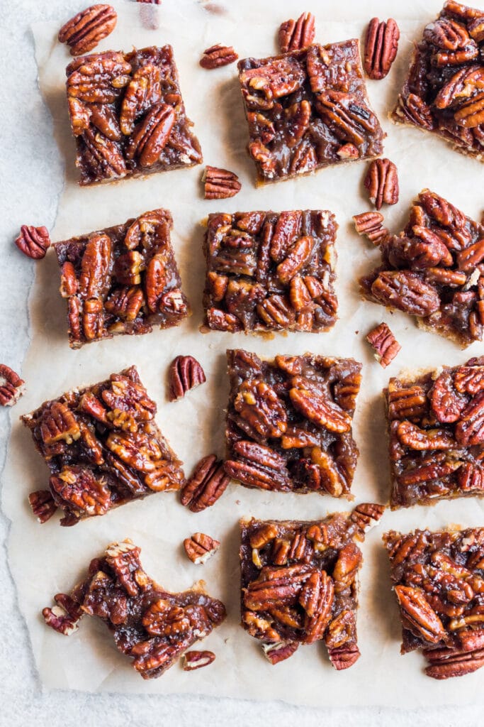 An overhead shot of Healthy Pecan Pie Bars cut on parchment paper