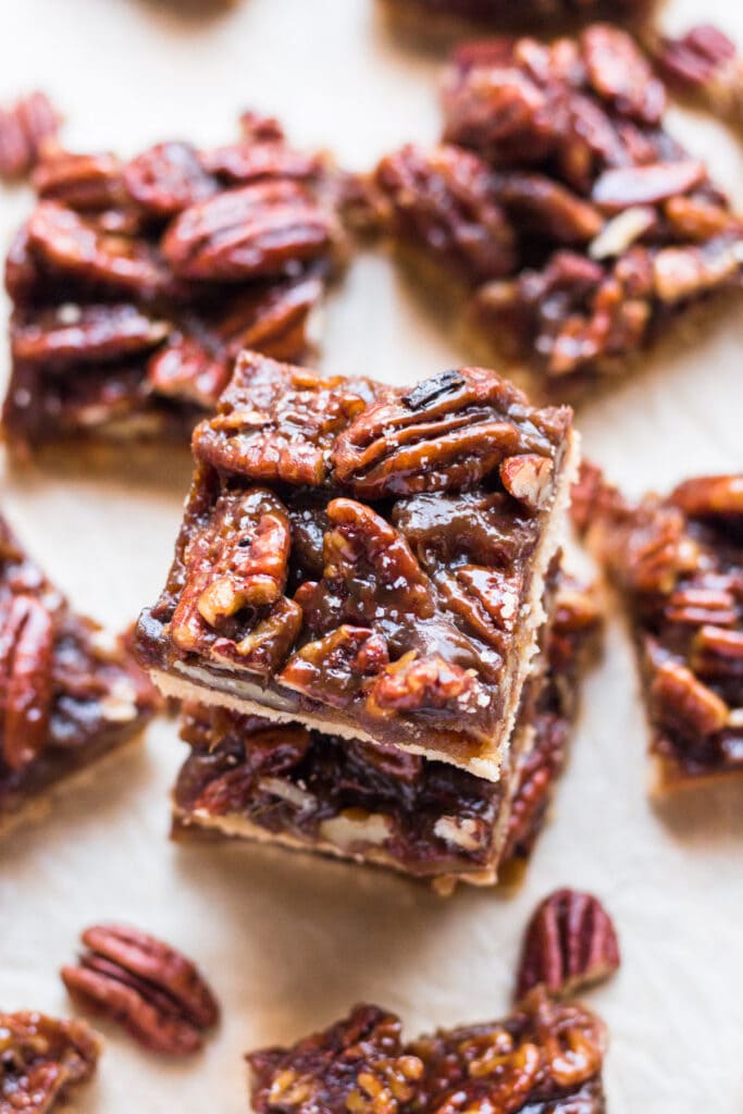 Paleo Pecan Pie Bars Stacked on top of one another with other healthy bars scattered around