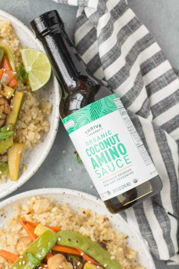 a bottle of coconut aminos on a grey background