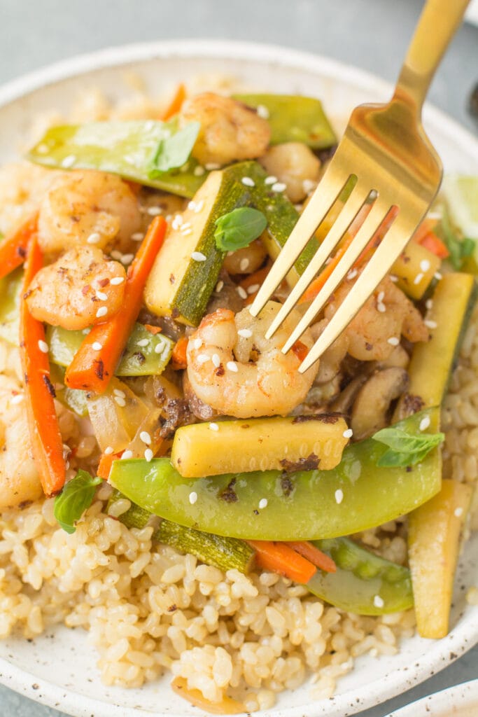Easy Shrimp Stir Fry on a plate with a fork getting a bite out of it.