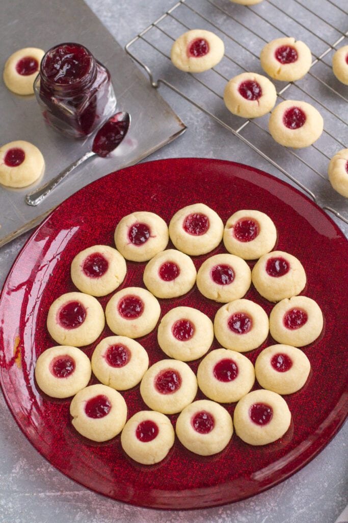 Thumbprint Cookies on a red christmas plate with cookies off to the side