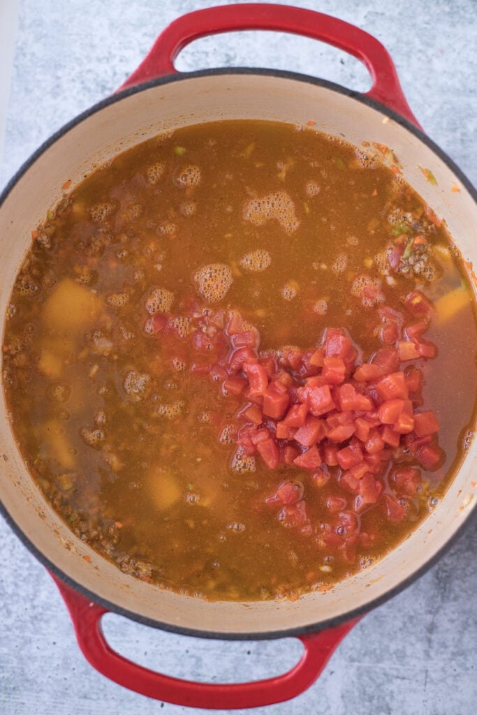 Cheeseburger Soup with tomatoes and broth being added in