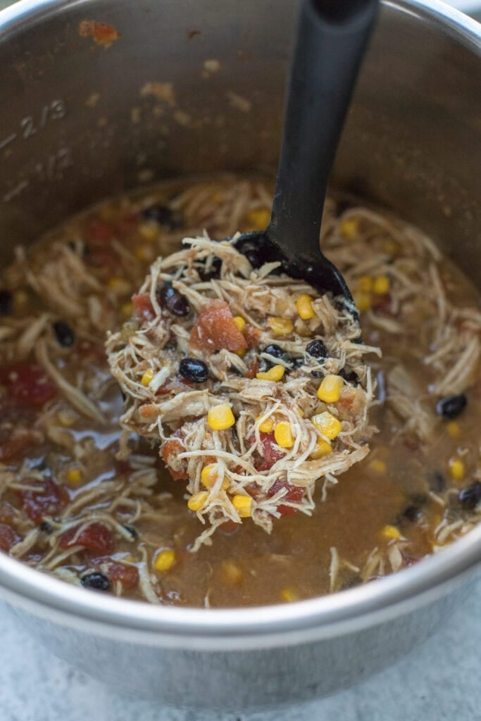 Chicken tortilla soup in an instant pot being ladled by a black ladle