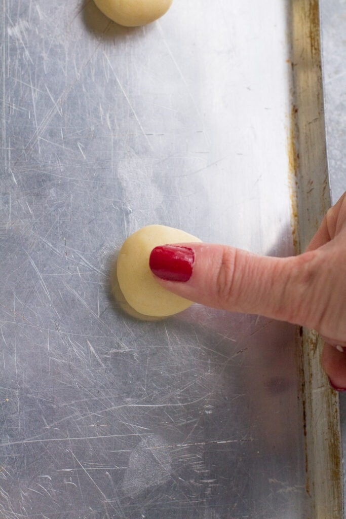 thumbprint cookie dough balls with a thumb pressing in to make an indent