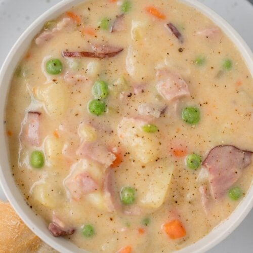 ham and potato soup recipe in a white bowl with bread on the side