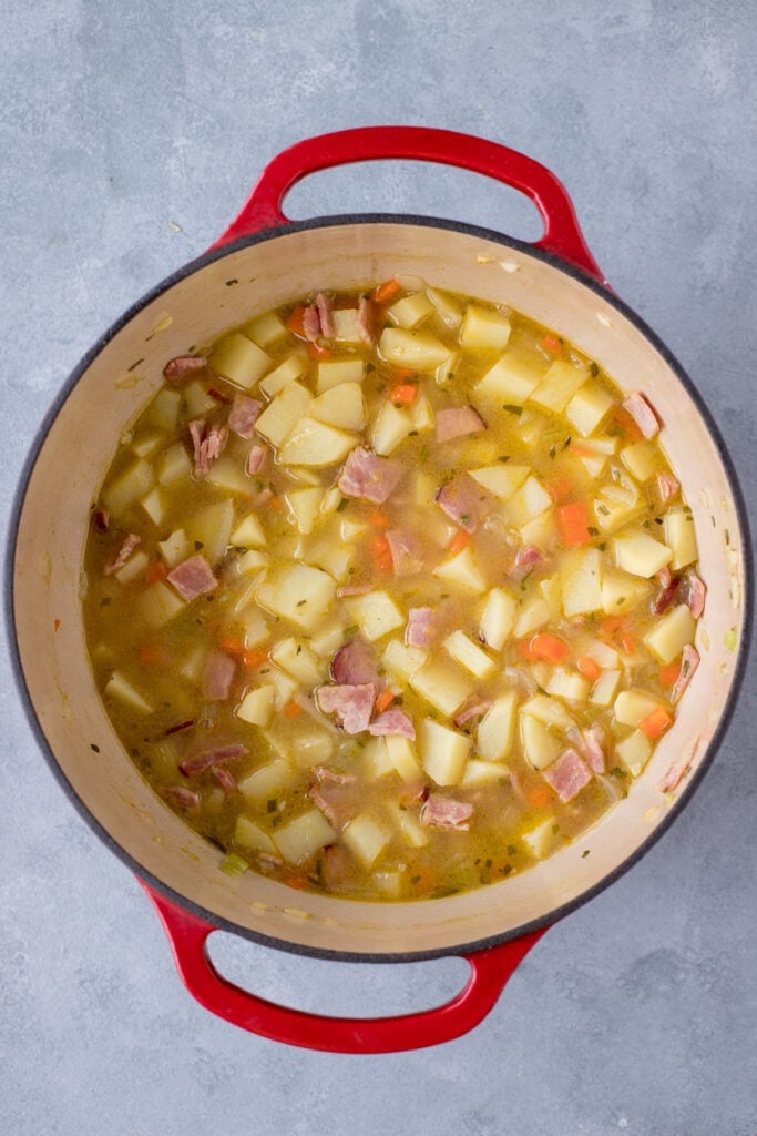 Potato soup with ham in a red dutch oven after cooking