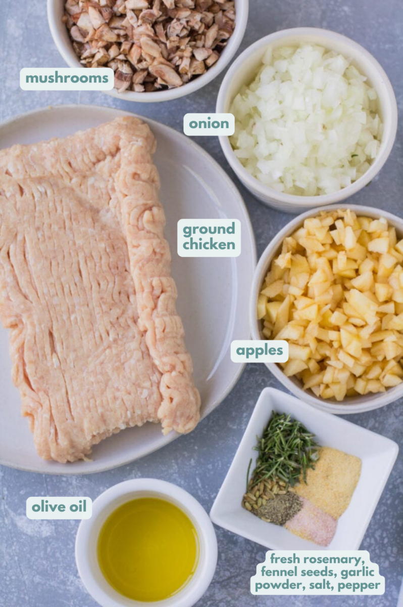 Ingredients for chicken breakfast sausage laid out in small bowls on a grey background.