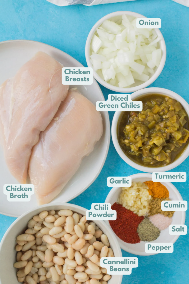 Ingredients for healthy white chicken chili in white bowls on a bright blue background