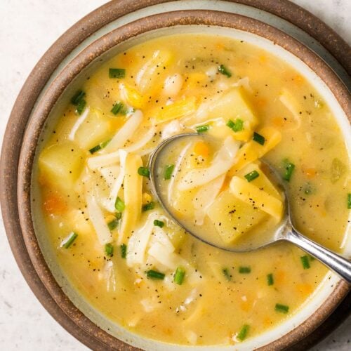 Instant Pot Potato Soup in a brown rimmed bowl with a spoon taking a scoop