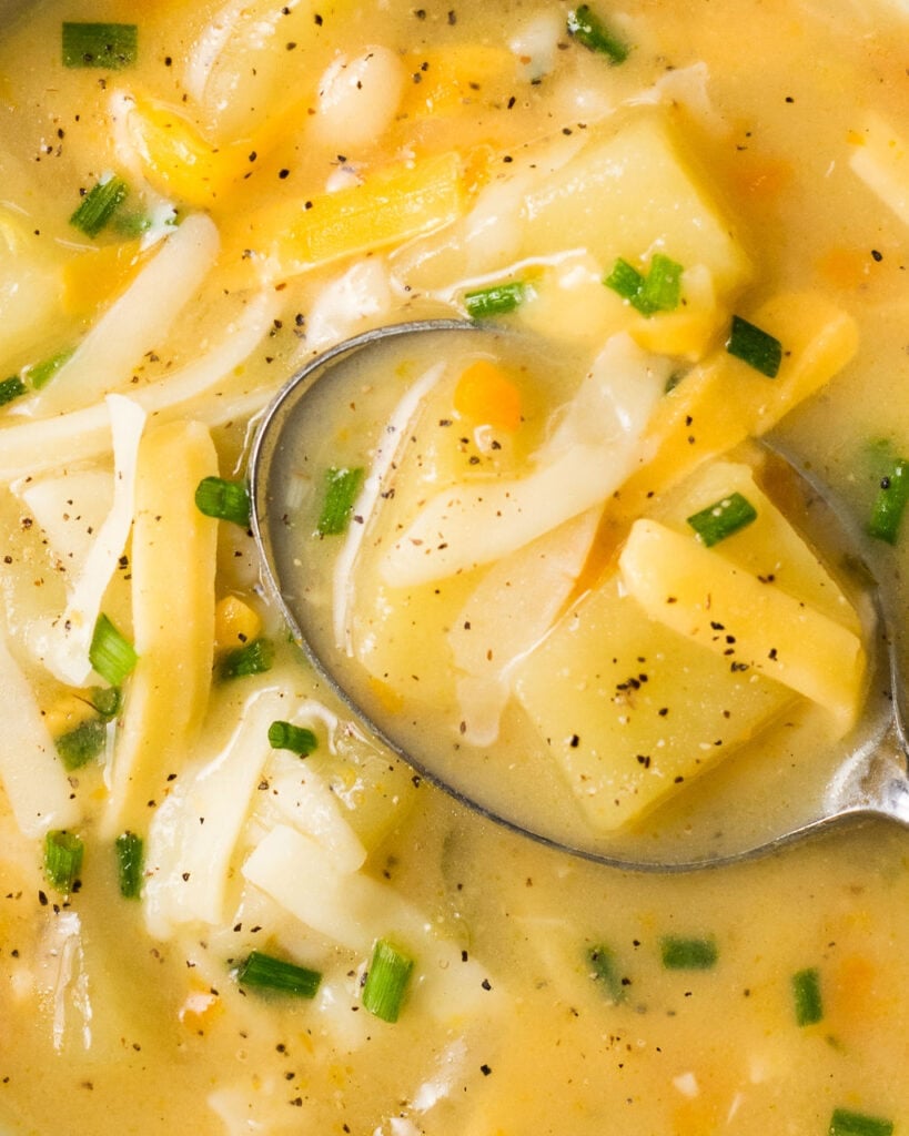 A close up of pressure cooker potato soup in a bowl with a spoon taking a scoop