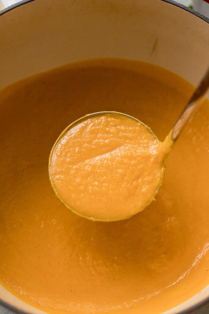 A ladel holding up a scoop of sweet potato soup