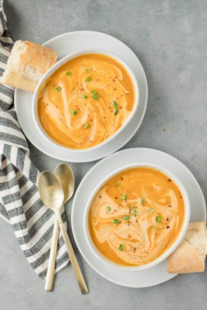 Two bowls of sweet potato soup on a grey background