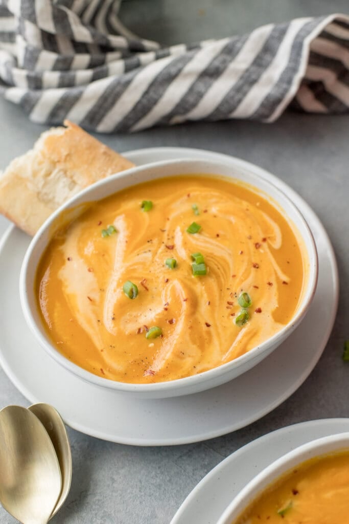 A close up of a Sweet Potato Soup Recipe in a white bowl with a striped linen in the background