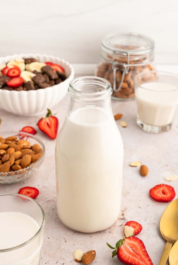 Whole30 Almond Milk in a glass milk bottle with almonds and strawberries on the side.