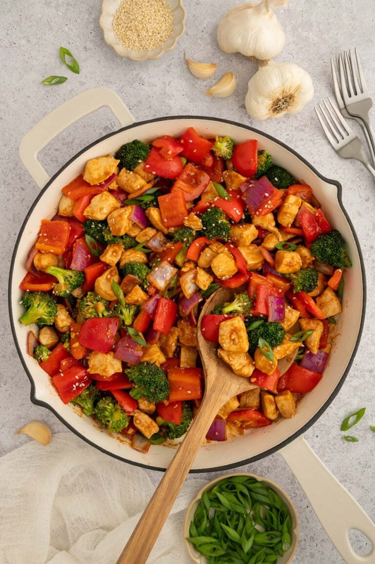 Healthy Sweet & Sour Chicken in a skillet with a wooden spoon in it.