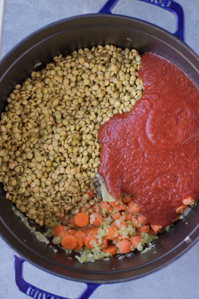 Lentil soup getting started to cook with lentils, crushed tomatoes and basil