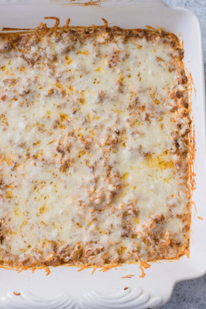 taco dip with meat in a white baking dish after being taken out of the oven