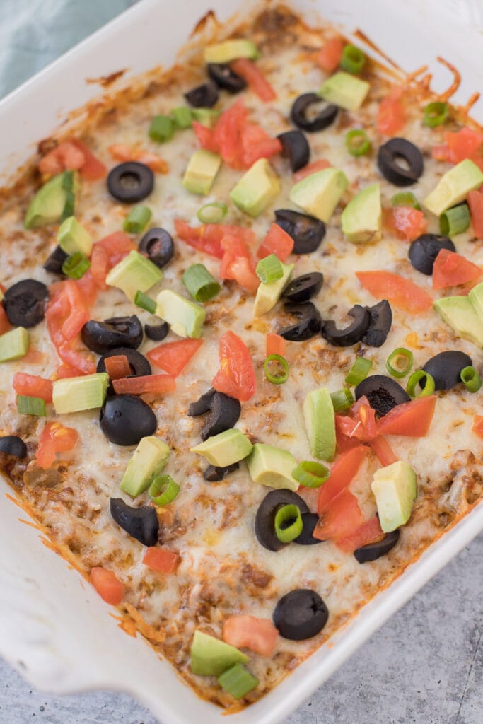 An overhead shot of the best easy taco dip in a white dish with lots of toppings