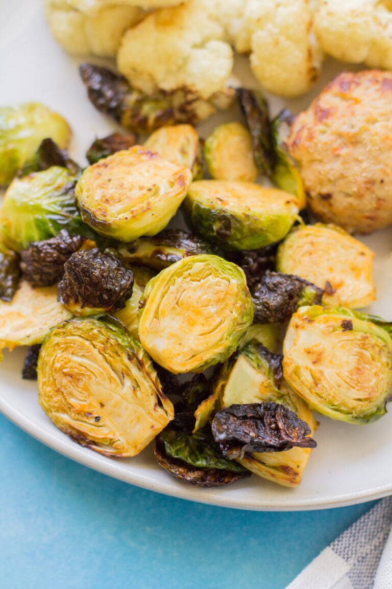 Buffalo Brussels Sprouts on a white plate on a bright blue background